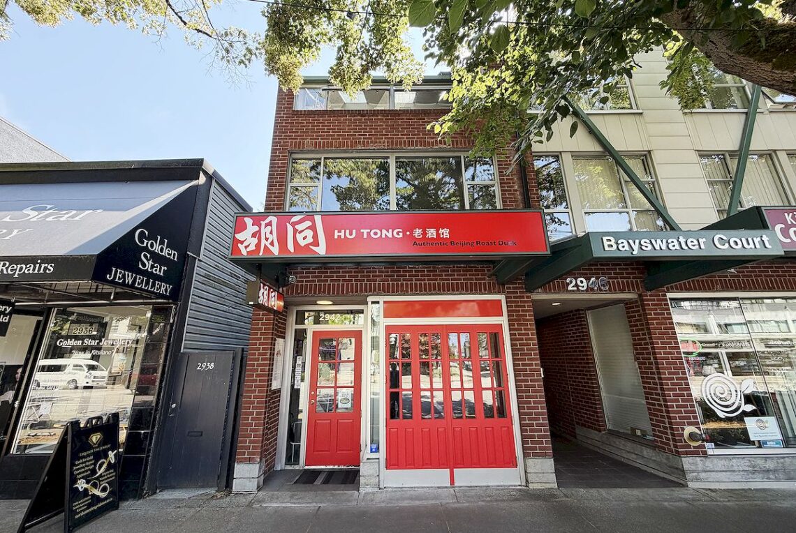 Turnkey Restaurant Business For Sale in Kitsilano | Full Commercial Kitchen & Liquor License 溫西 Kitsilano 黃金地段 10 年老字號餐飲生意轉讓 | 全商業廚房+酒牌 | Selling & Managing Vancouver Real Estate Street-level view of a Chinese restaurant with red double doors and a red sign reading 'HU TONG Authentic Beijing Roast Duck' between a jewellery shop and a courtyard entrance on a sunny day.