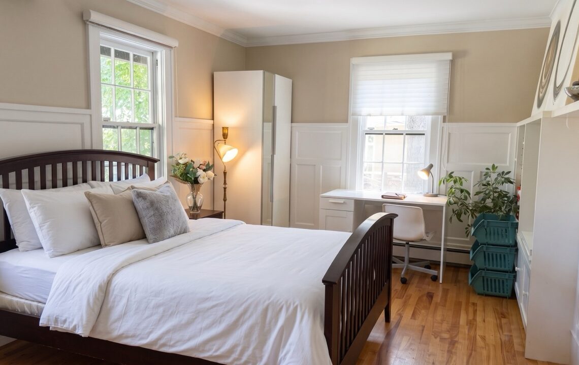 Vancovuer 1-Bedroom Near Magee Secondary for Students 溫西近Magee中學一睡房分租(學生友好) | Selling & Managing Vancouver Real Estate Bright, tidy bedroom with a dark wood bed, white linens, and a desk near a window for study or work.